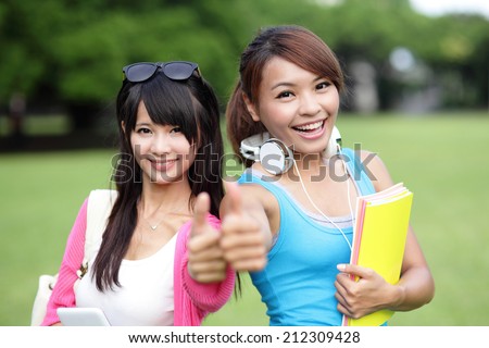 Happy girl College students smile show thumb up sign to you on campus lawn, asian