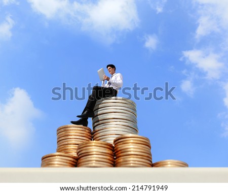 Successful business man working and using digital tablet pc on growth money stairs coin with sky
