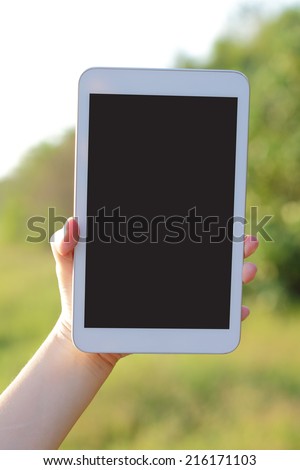 Using digital tablet pc with empty screen , nature green background, screen is great for your design copy space