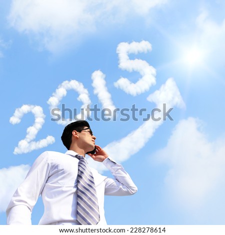 Successful Business in new year - business man talking on smart phone with growth arrow and 2015 new year cloud in sky