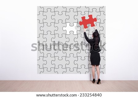 business woman hold jigsaw puzzle - Back view of business woman making a puzzle on the wall