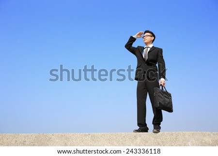 Successful business man purposefully looking away with blue sky, asian male
