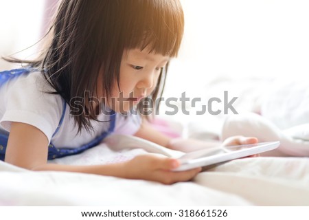child girl happy play game with tablet PC. asian child
