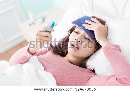 Sick Woman caught Cold and fever or Headache and lying on bed at home. asian female