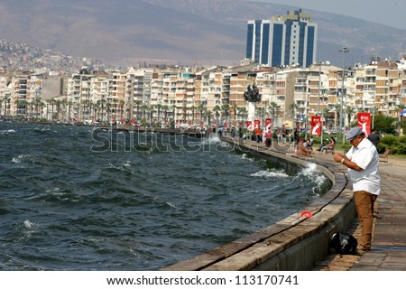 IZMIR, TURKEY - JUNE 26: A man fishing at Alsancak coastline in Izmir, June 26, 2005 in Izmir, Turkey. Izmir is the third most populous city in Turkey. This coastline public name is Kordon.