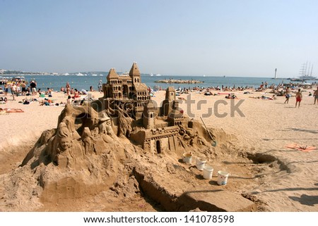 CANNES, FRANCE - JULY 24: Sand castle and sunbathing people at Cannes Beach on July 24, 2006 in Cannes, France. Cannes beachfront, considered between 5 best urban beach of the Europe.