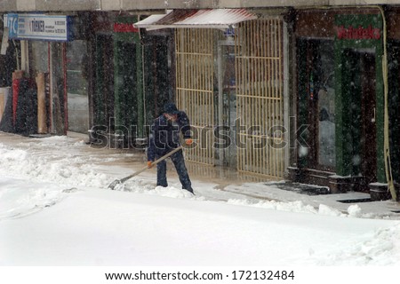 ISTANBUL, TURKEY - JANUARY 23: Man shoveling snow from the sidewalk in front of his shop on a snowy day in Fatih District on January 23, 2007 in Istanbul, Turkey.