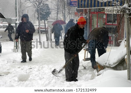 ISTANBUL, TURKEY - JANUARY 23: Man shoveling snow from the sidewalk in front of his shop on a snowy day in Eminonu District on January 23, 2007 in Istanbul, Turkey.