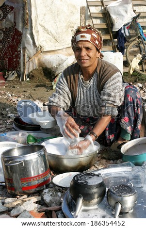 ISTANBUL, TURKEY - JANUARY 8: Old Gypsie woman washing dishes at Silivri Gypsy Camp on January 8, 2008 in Istanbul, Turkey.