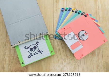 Stack of colorful floppy disks and a floppy disk drive on a wooden table