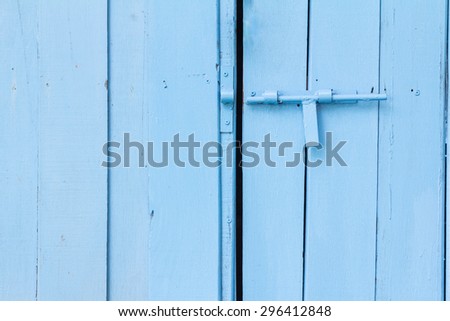 Blue painted wooden wall and door with bolt