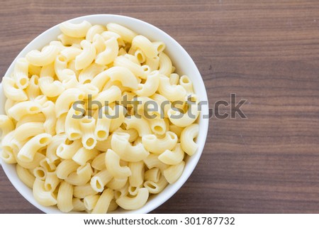 Boiled macaroni pasta in a white dishes on a wooden table