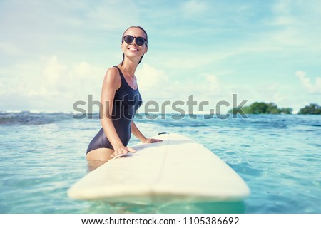 Extreme Water Sport. Surfing. Healthy Athletic Young Surfer Girl With Sexy Fit Body Holding Surf Board While Standing In Clear Water, Summer Vacation. Lifestyle. Leisure, Hobby, Wellness, Fitness.