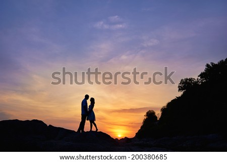 Silhouette of a couple in love on a sunset tropical background.