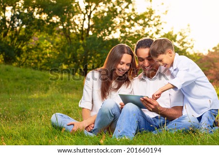 Portrait of an international family playing tablet PC in in the park.
