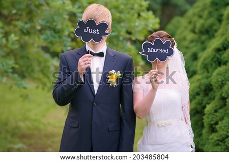 Bride and groom holding just married signs in front of their faces