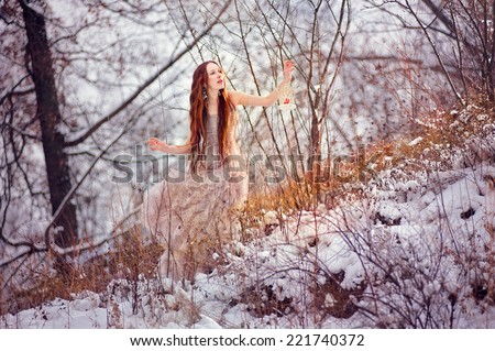 Young beautiful red haired girl lost in the winter magic forest with the old fashioned lantern in her hand