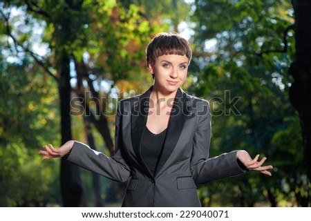 Portrait of Helpless young short hair business woman shrugs her shoulders looking at camera outdoors