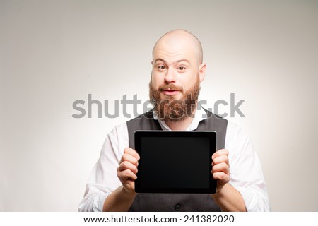 Join a digital age. Cheerful young bearded man showing a screen of digital tablet and smiling at camera