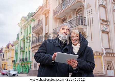 family, age, tourism, travel and people concept - senior couple with digital tablet and city guide on street