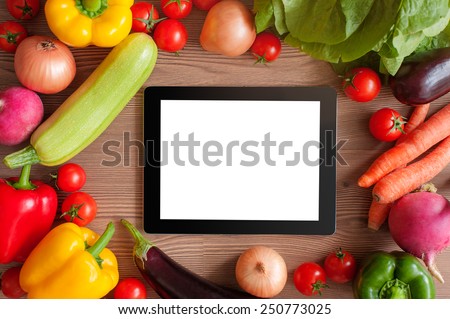 Cooking concept. Digital Recipe book. Tablet pc and ingredients for cooking vegetables over wooden background. Top view