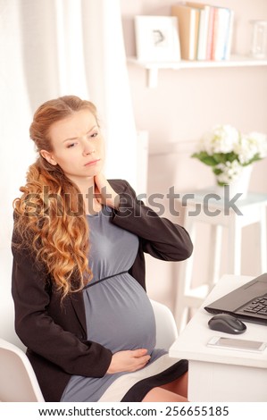 Tired pregnant woman. Depressed pregnant businesswoman holding head in hand while sitting at her working place in office