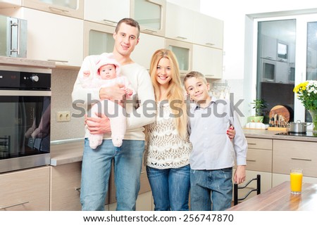 Happy family. Portrait of attractive smiling family standing together in the kitchen.
