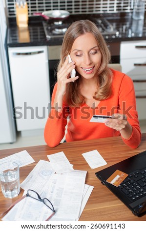 Happy Woman talking by mobile phone shopping online with credit card and computer. Internet Shopping