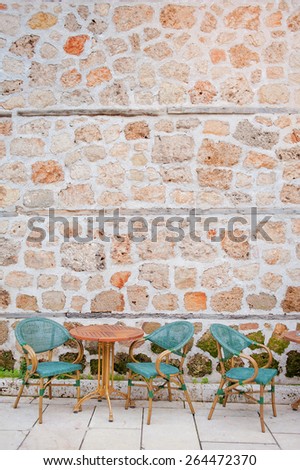 Outdoor restaurant summer terrace at day - old vintage cafe with wooden table in old town against stone wall.