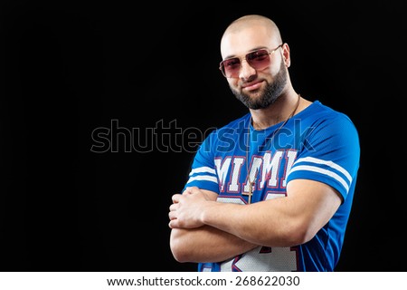 Rap and hip hop. Confident young latin man standing against black background with arms crossed.