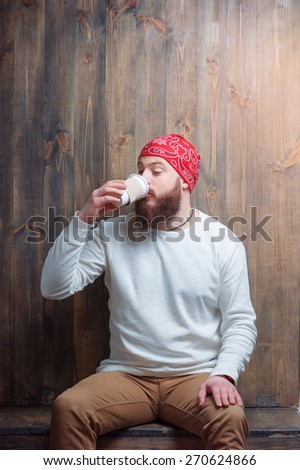 Coffee for wake up. Young bearded man drinking cup of beverage.