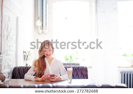 Youth and technology. Young attractive long hair woman using smartphone while sitting at cafe.
