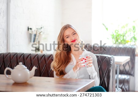 Drinking tea. Young beautiful long hair woman holding cup of beverage while sitting at cafe.