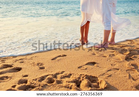 Romance concept. Honeymoon at the sea. Loving couple on the beach. Close up male and female feet on the sand.
