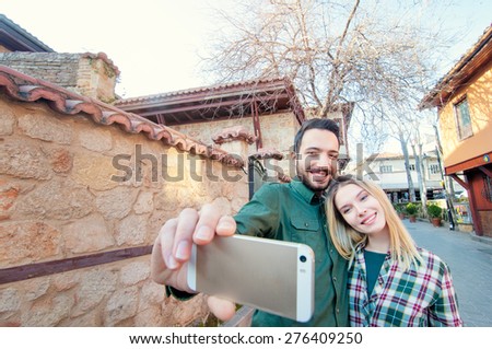 Catching the bright life moments. Beautiful young loving couple making selfie with smart phone and smiling while traveling by Europe.