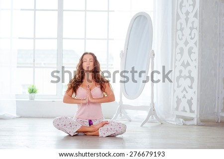 Morning yoga. Attractive young woman sitting in lotus position on floor with eyes closed.