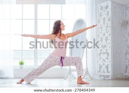 Morning yoga. Attractive young woman stretching on floor in her apartment.