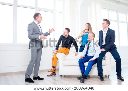 Good mood and creative work. Group of happy young business people laughing and listening their colleague while sitting on the couch.