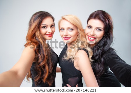 Beauty, friendship, youth and technology. Studio portrait of Three gorgeous young women taking selfie looking at camera.