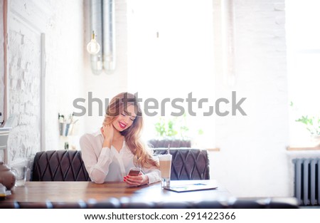 Youth and technology. Young attractive long hair woman using smartphone while sitting at cafe.