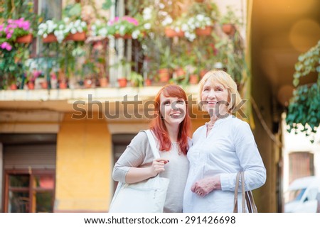 Outdoor family portrait of  Middle aged Mother and her Adult Daughter  walking on city street.