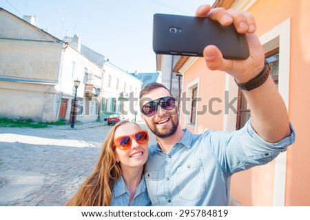 Catching the bright life moments. Beautiful young loving couple taking selfie with smart phone and smiling while traveling by Europe.