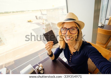 Enjoy traveling! Vacation Selfie. Beautiful young woman in hat taking selfie while waiting for boarding in the airport.