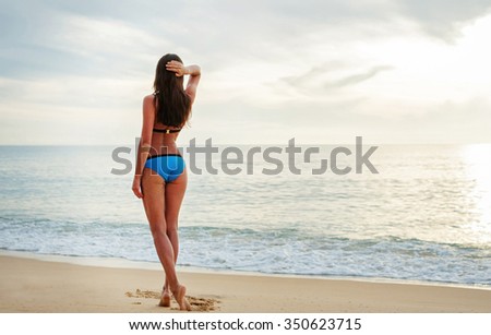 Vacation on the sea. Back view of attractive slim brunette woman on the sand beach.