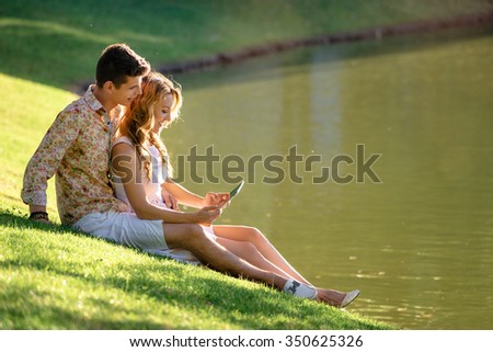 Romance and love. Dating in park. Loving couple sitting together on grass near the lake.