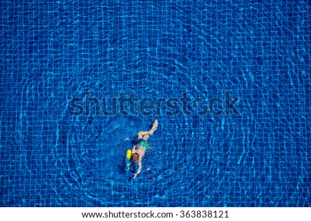 Playing in water. Top view of little boy swimming in the pool.