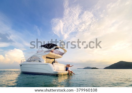 Friendship and luxury vacation. Two happy young women sitting on the yacht deck looking and pointing away sailing the sea.