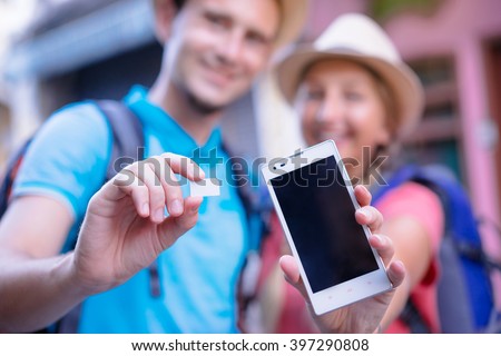 Travel and communication. Young couple of travelers showing sim-card and screen of smartphone. Focus on hands.