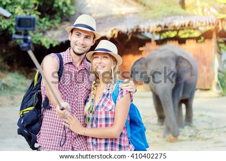 Tourism and technology. Traveling friends taking selfie on action camera together against elephant in zoo.