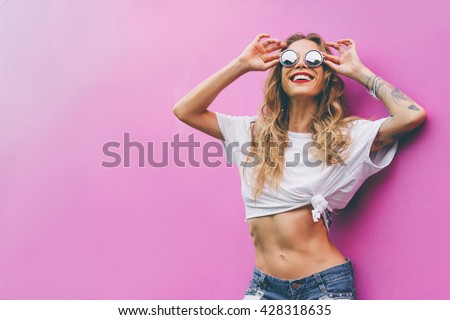 Fun and colorful. Young pretty happy woman in shorts posing against pink wall.